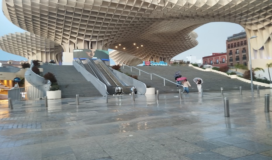 Personas con paraguas caminando por las Setas de Sevilla.